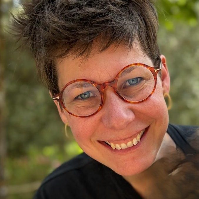 intervenante Femme souriante portant des lunettes au style rétro, en extérieur.